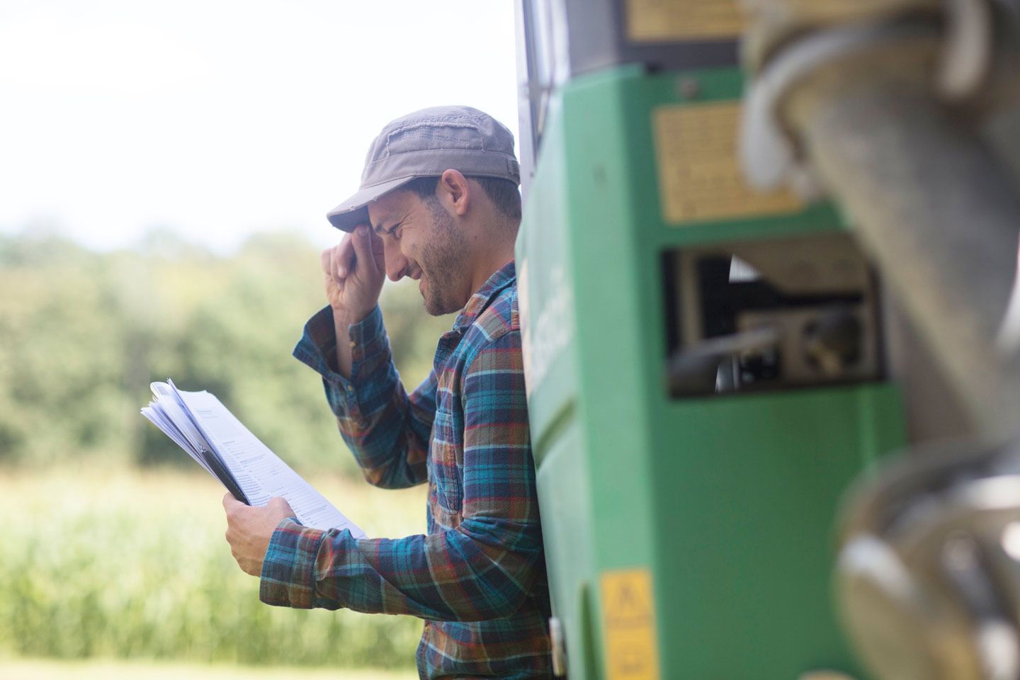 Ein Landwirt lehnt an einen Gefährt und liest Unterlagen.