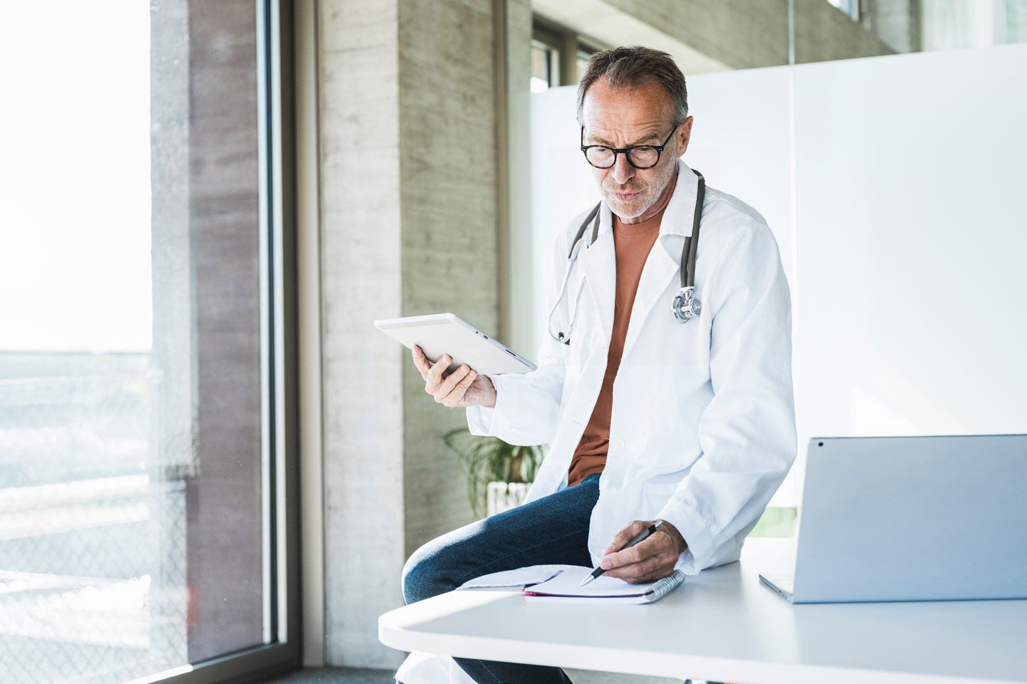 Arzt mit Tablet macht Notizen.