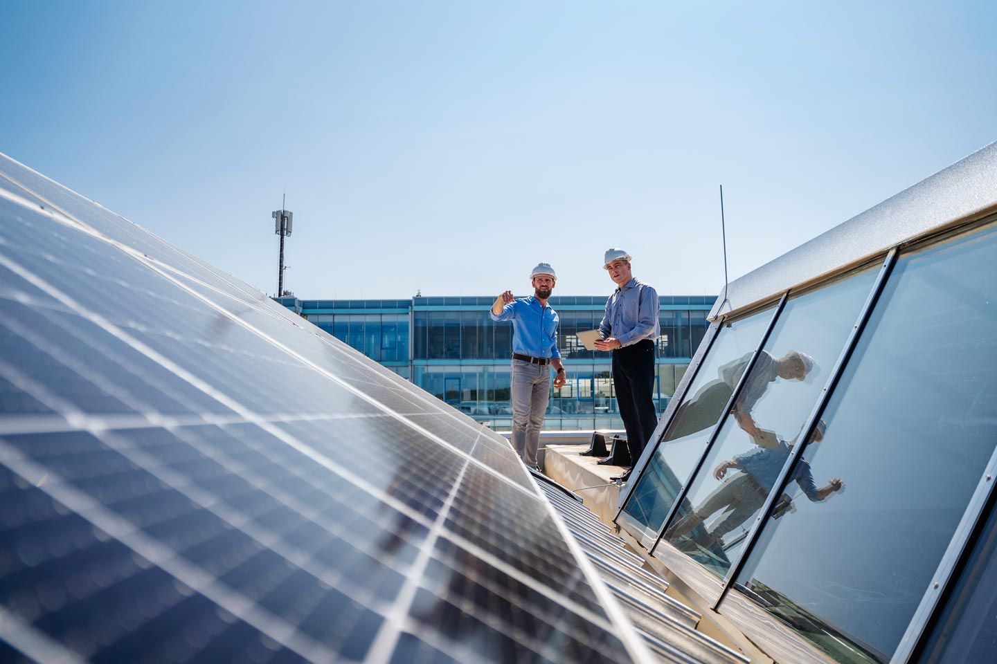 Fachkräfte begutachten eine Photovoltaikanlage auf dem Dach.