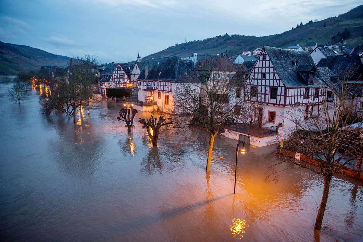 Straße in einem histirischen Fachwerkdorf, komplett überflutet, mit teilweise im Wasser stehenden Bäumen und Laternen.