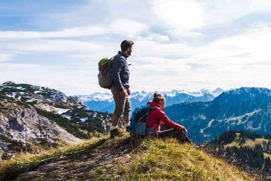 Wanderer sitzen auf einem Berggipfel und genießen die Aussicht.