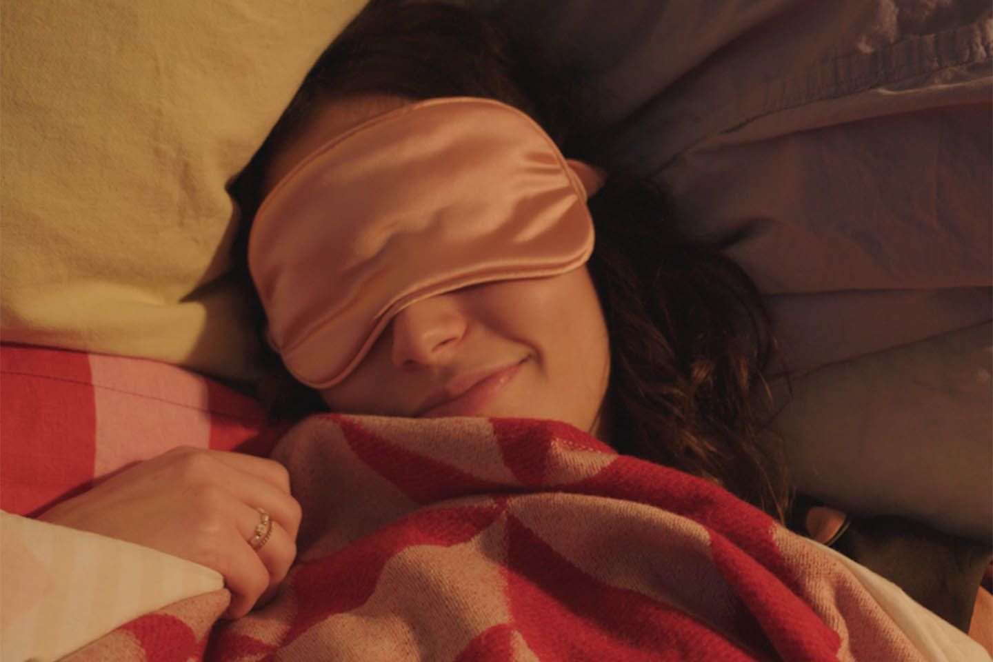 Eine Frau liegt mit einer Schlafmaske im Bett.