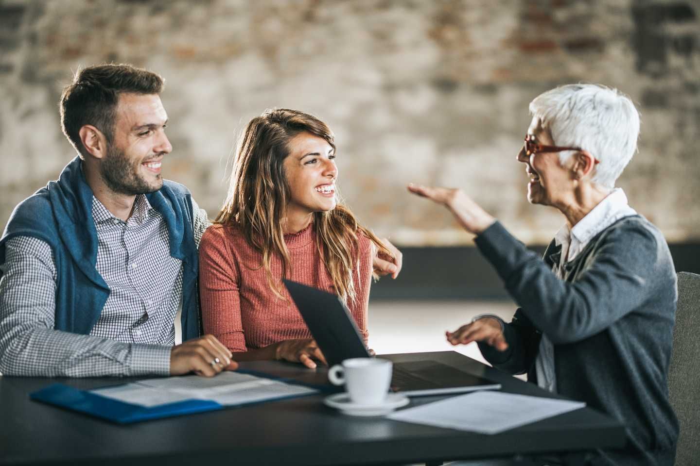 Ein Paar sitzt lächelnd einer Beraterin gegenüber.