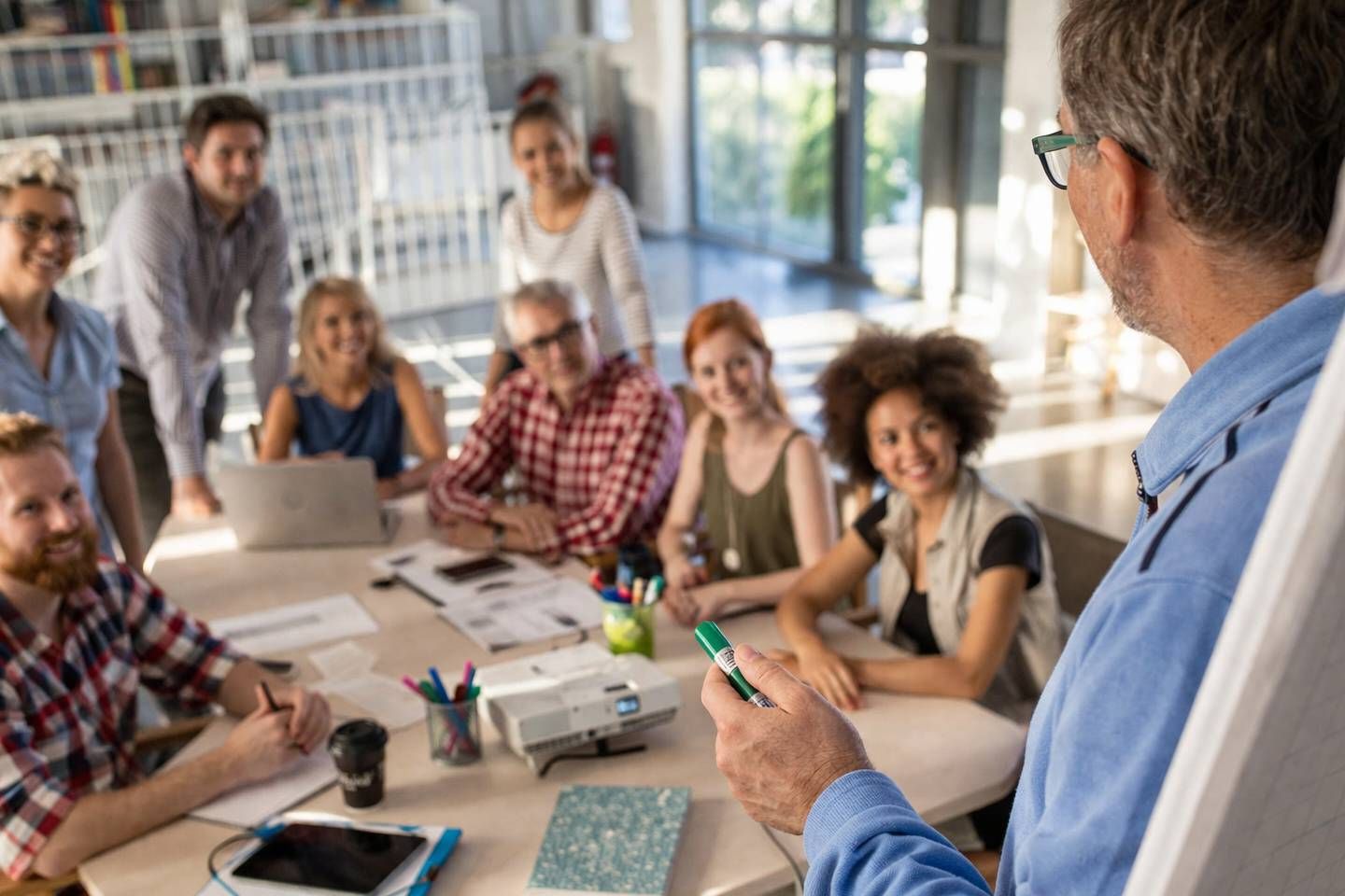 Dozent erklärt vor aufmerksamem Team Inhalte am Flipchart.