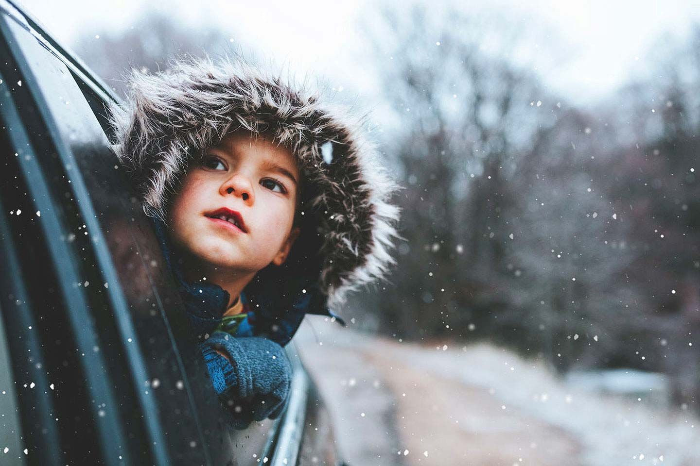 Junge schaut aus dem Auto und bewundert den Schneefall.