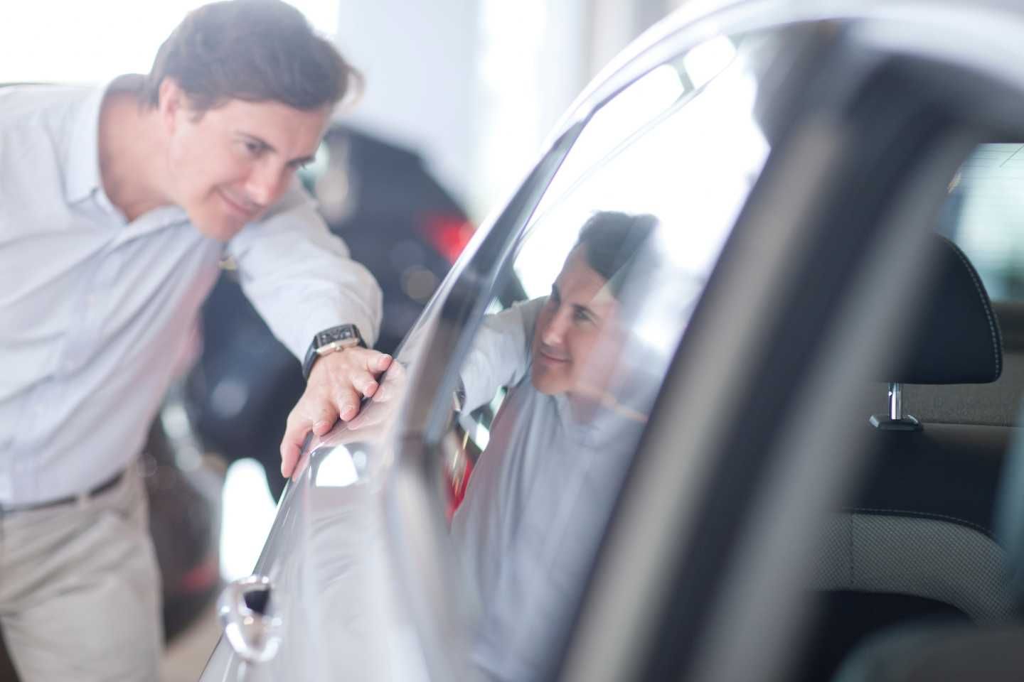 Ein Mann betrachtet die Seitenfläche eines Autos.