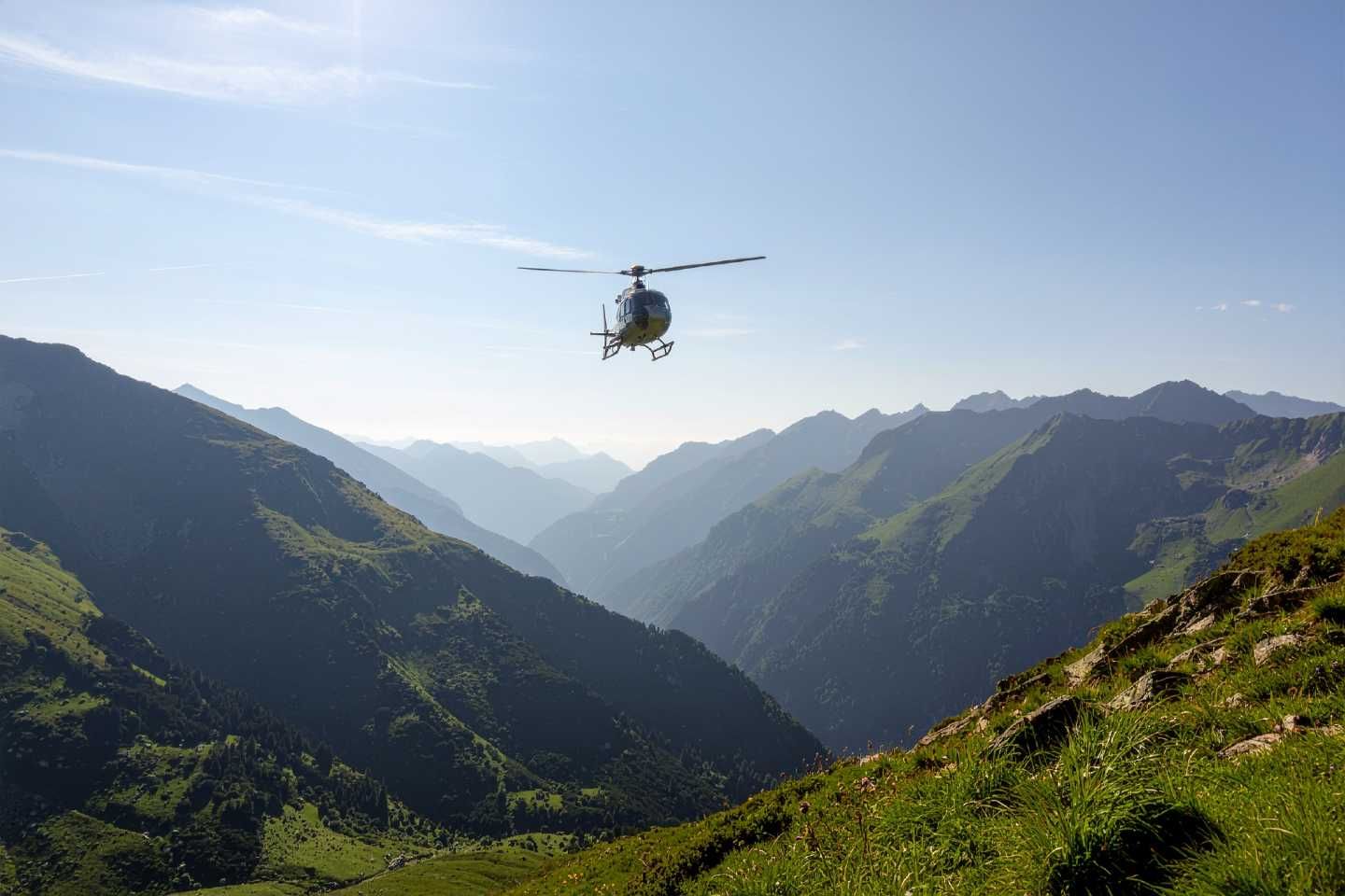 Hubschrauber fliegt über eine Berglandschaft.