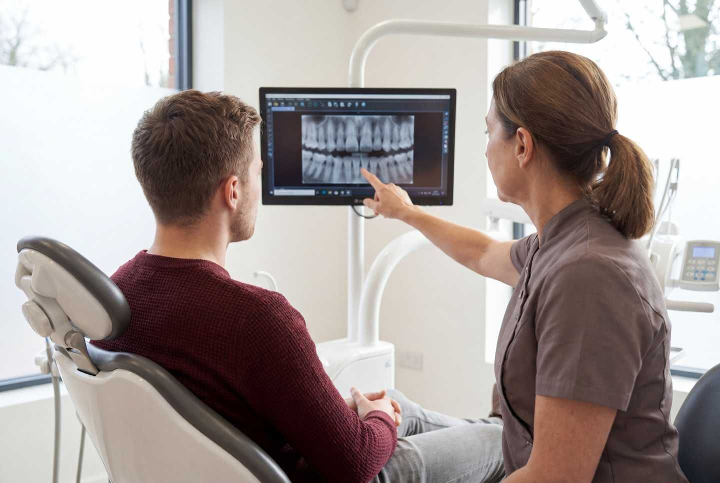 Eine Zahnärztin erklärt dem Patienten anhand einer Röntgenaufnahme seinen Kreuzbiss.