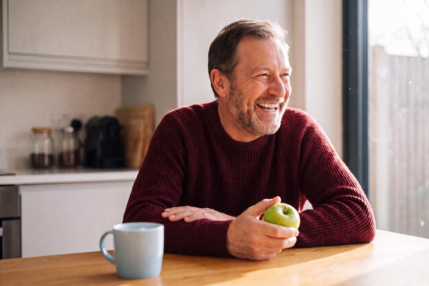 Mann lächelt und hält Apfel in der Hand.