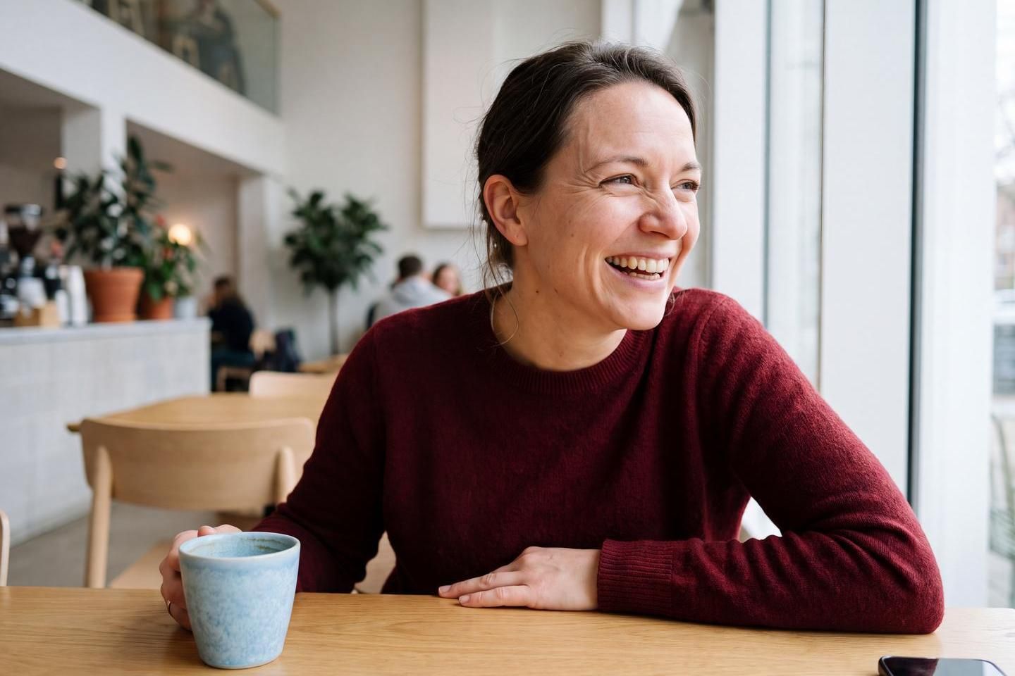 Frau lächelt und hält Tasse in der Hand. (Bild KI-unterstützt generiert)