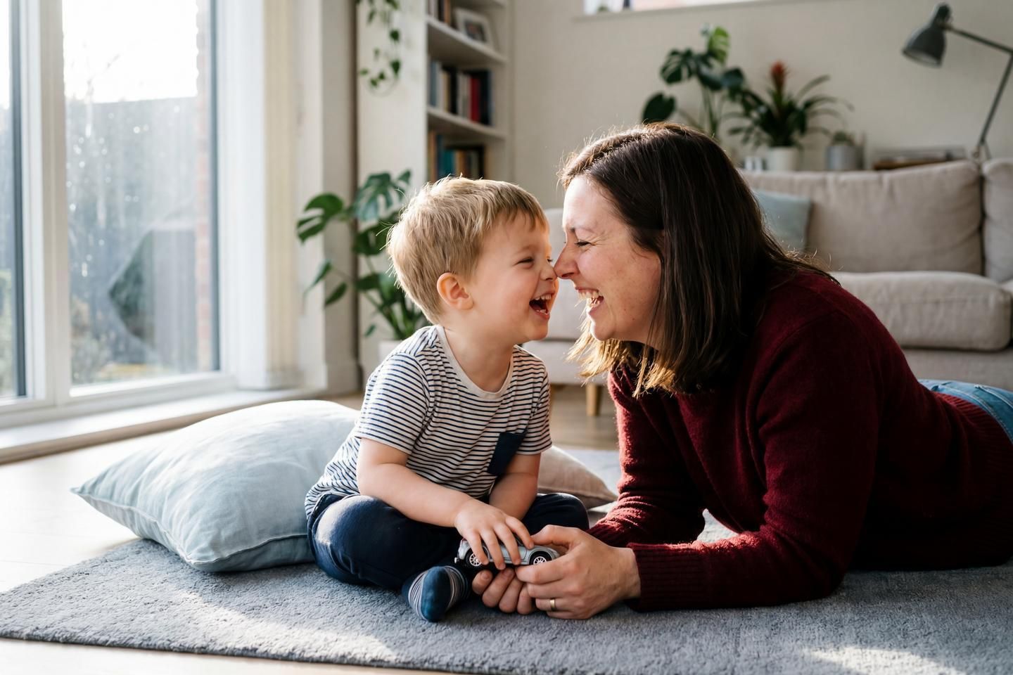 Eine Mama spielt ausgelassen mit ihrem Sohn im Wohnzimmer.