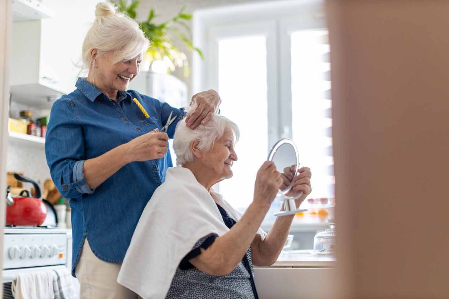 Eine Frau schneidet einer älteren Frau die Haare.