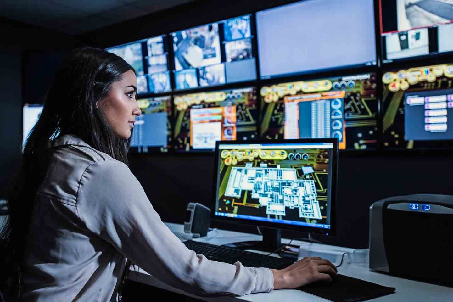 Eine Frau überwacht mit Monitoren ein Gebäude.