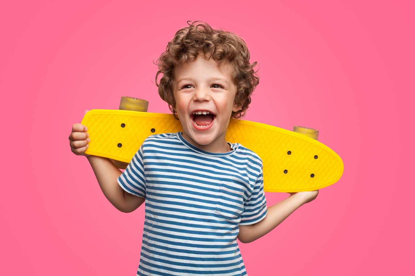 Eine Junge lacht und hat ein Skateboard.