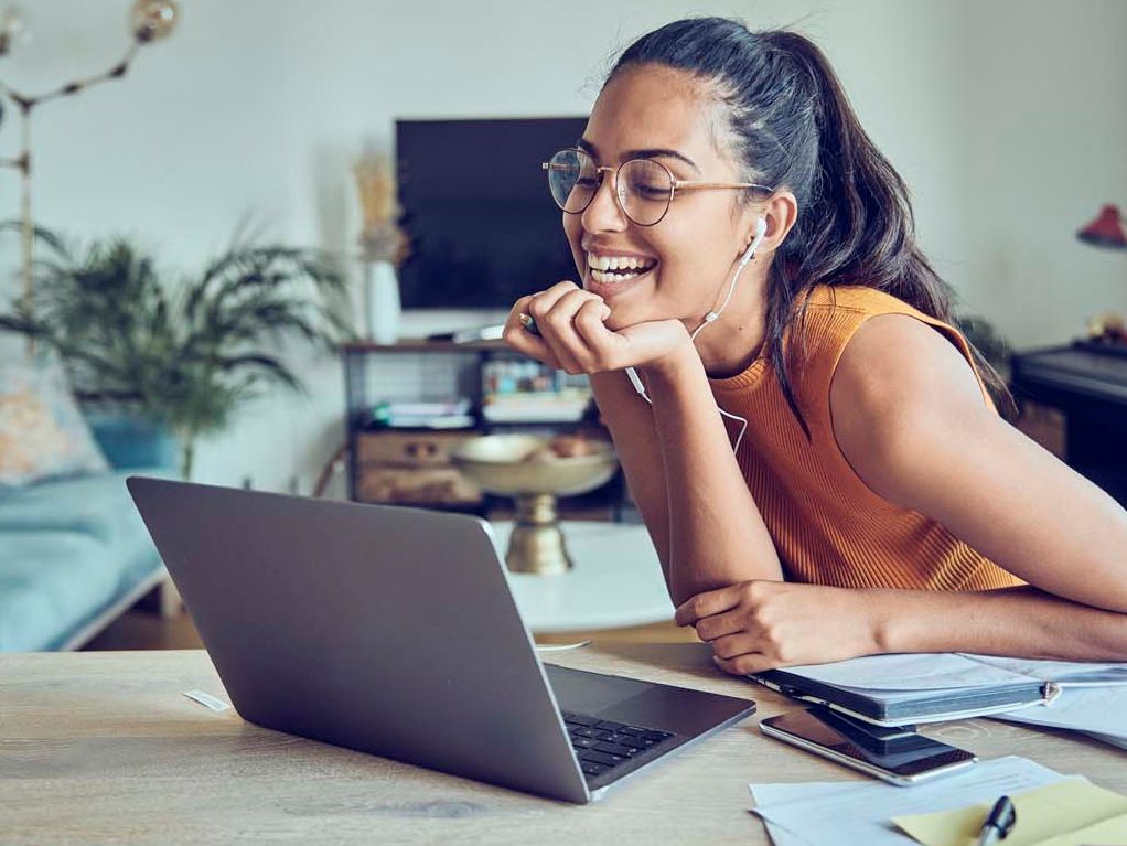 Eine junge Frau strahlt in ihren Laptop hinein. 