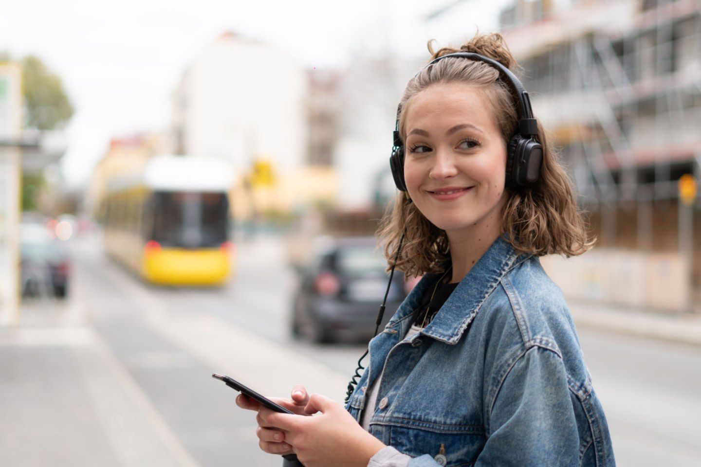 Lächelnde Frau mit Kopfhörern und Smartphone