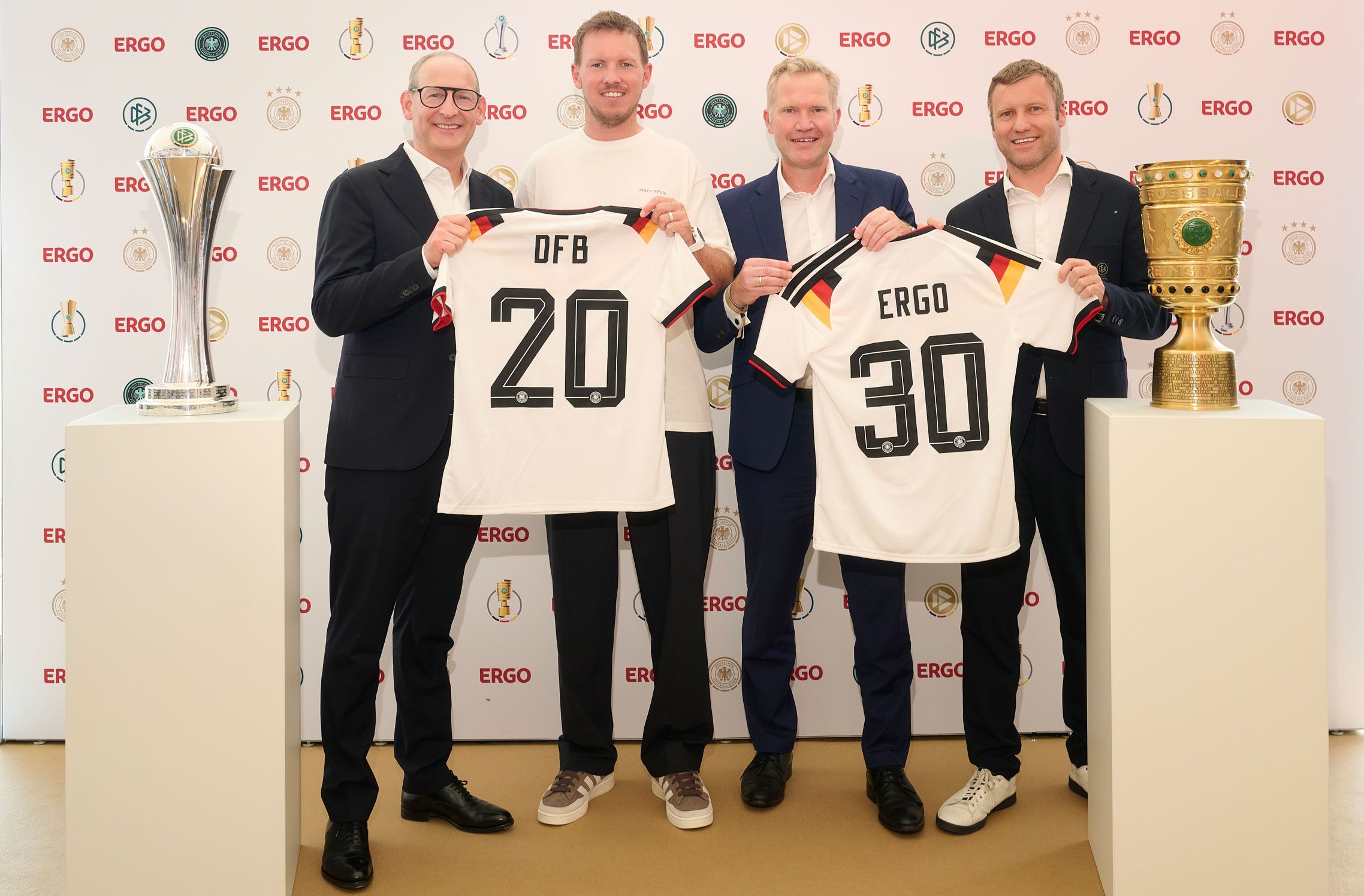 Vier Männer halten zwei Trikots in die Kamera..