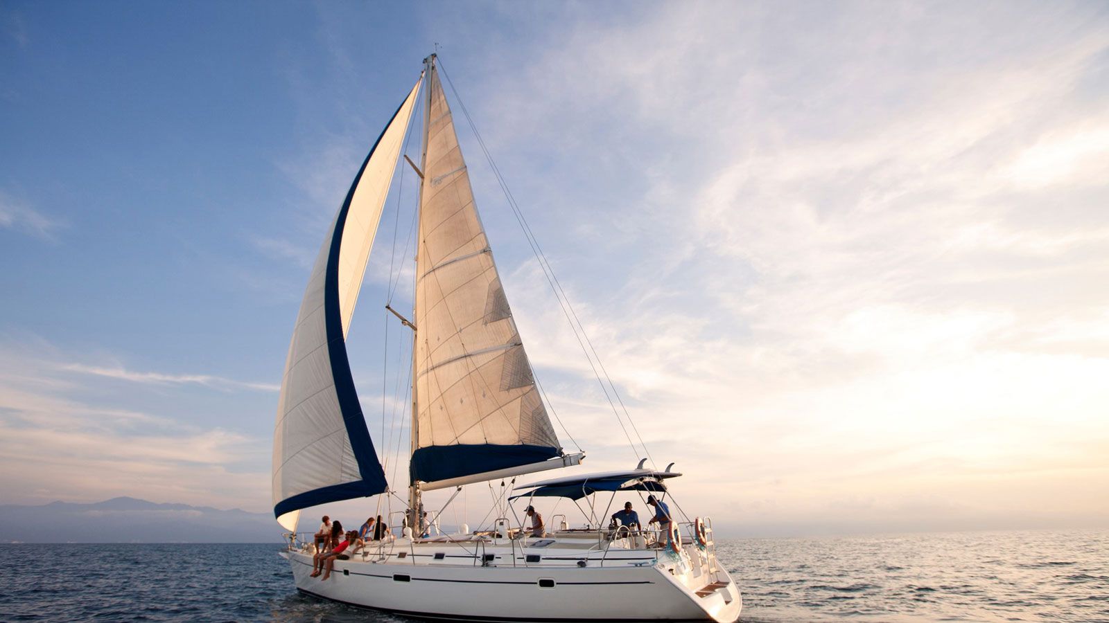Ein Segelboot mit mehreren Personen fährt über den Ozean.