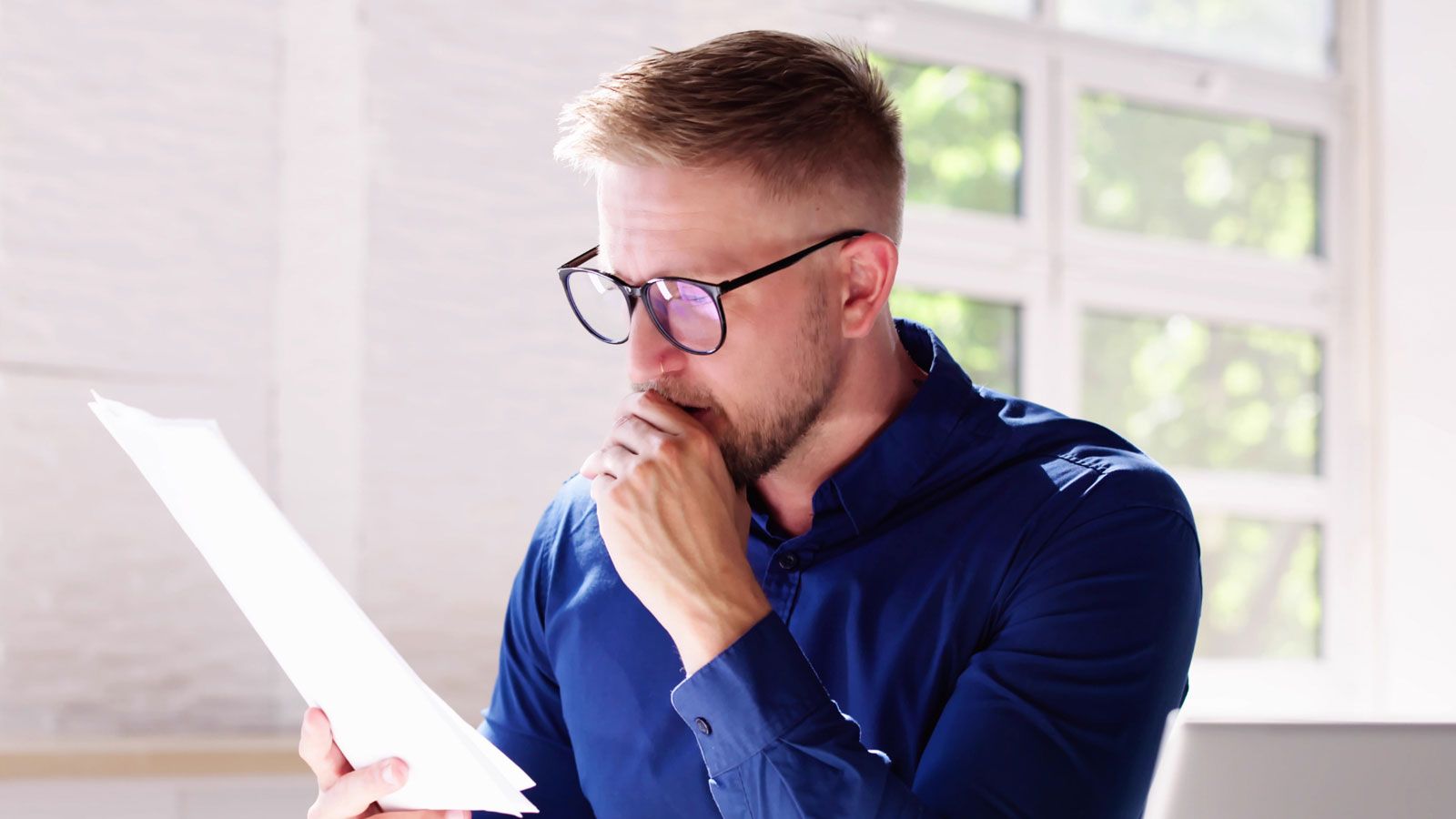 Ein Mann mit Brille schaut auf ein Blatt Papier.