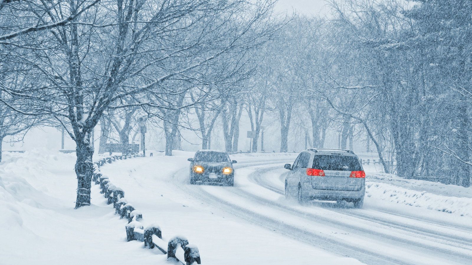 Schnee auf der Straße, Autos fahren vorsichtig durch winterliche Bedingungen.