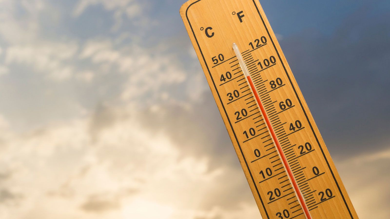 Steigendes Thermometer mit Himmel im Hintergrund