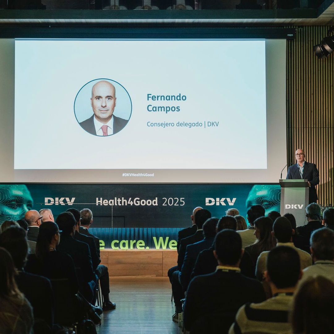 A man stands on a stage at a lectern in front of a seated audience.
