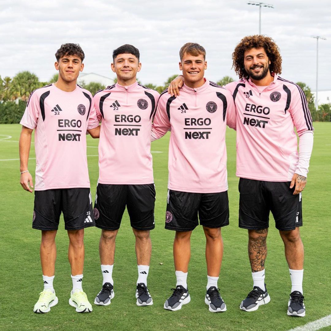 Four footballers in pink jerseys, on which ERGO Next can be recognised as the sponsor. 