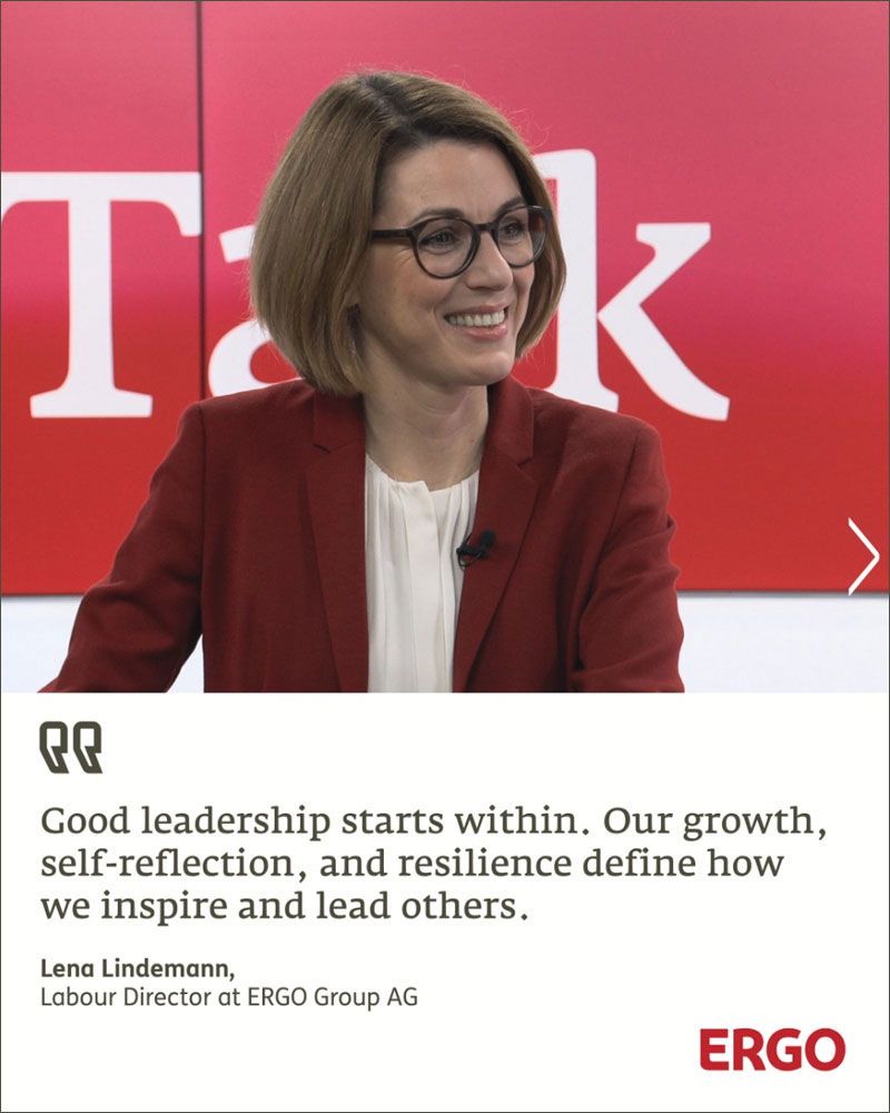 A blonde woman wearing glasses, a red blazer, and a white blouse.