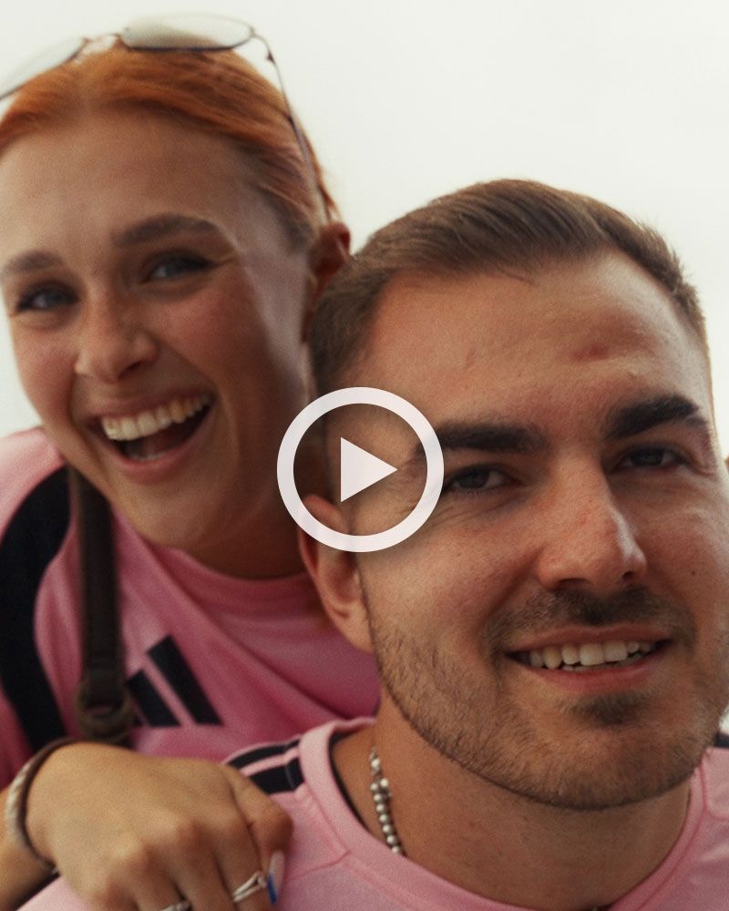 A couple wearing pink Inter Miami shirts are smiling at the camera.