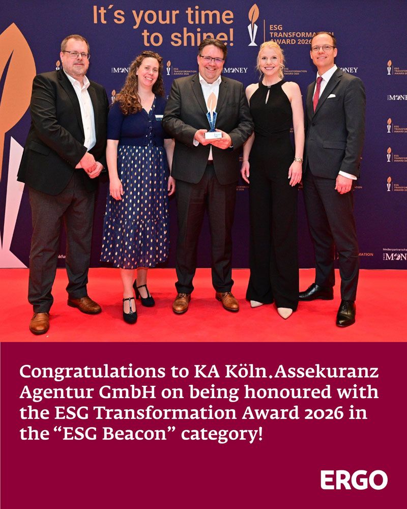 Three men in suits and two women in evening gowns are standing on a red carpet, holding an award up to the camera.