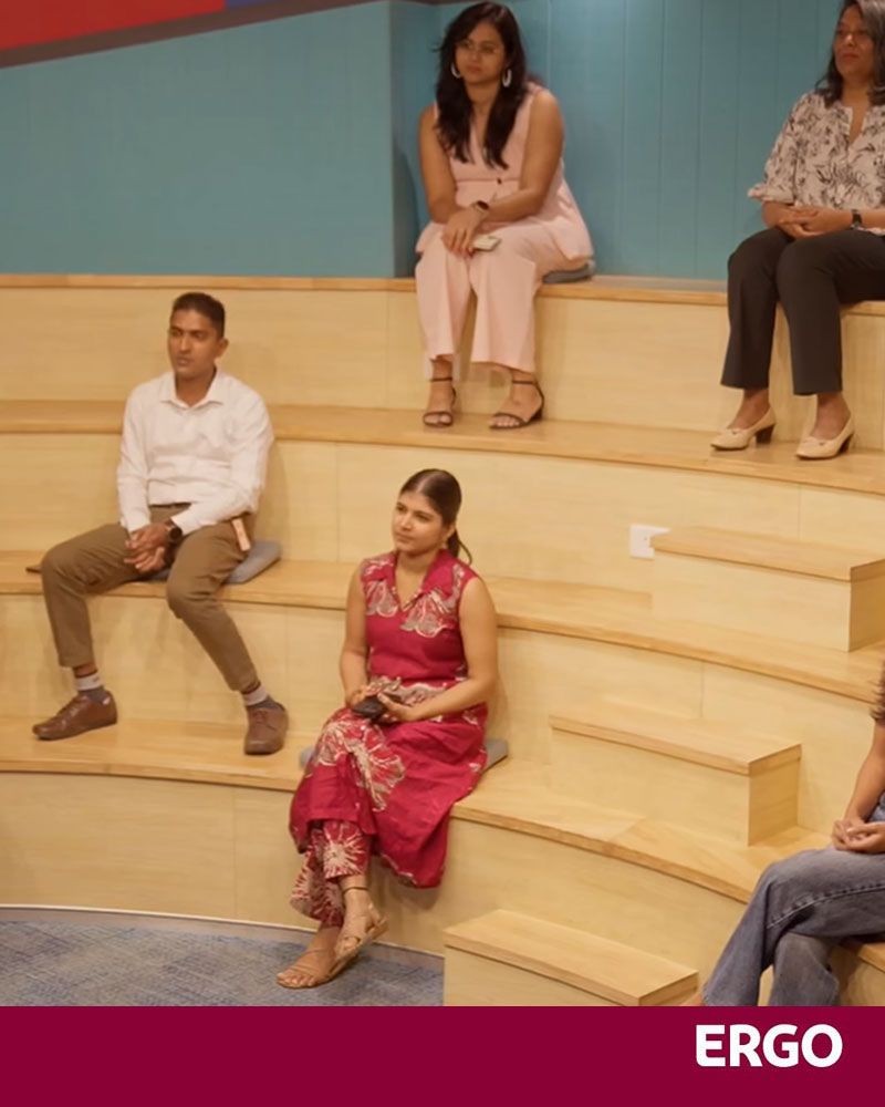 Five young Indian students are sitting on benches in the lecture theatre.