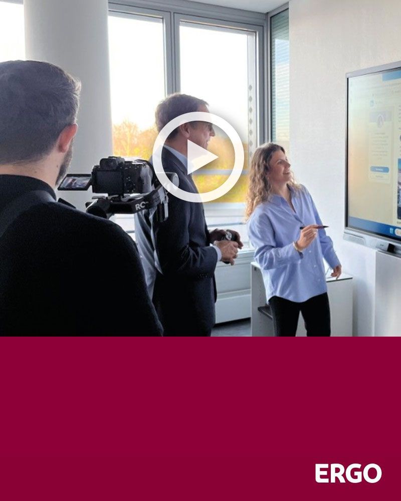 A woman and a man are standing in front of a cameraman.