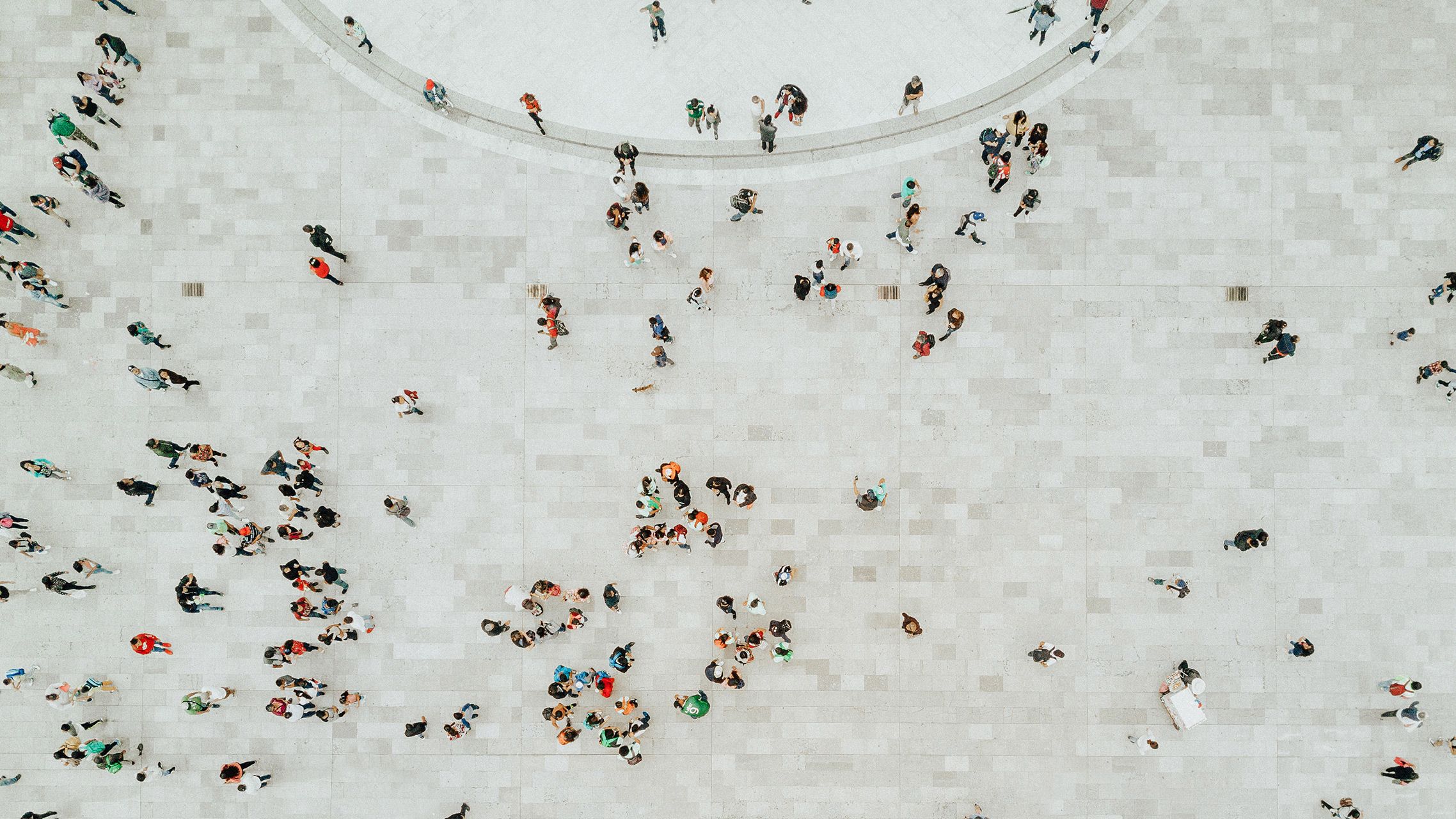 Aerial view of a light paved square with several groups and individual people