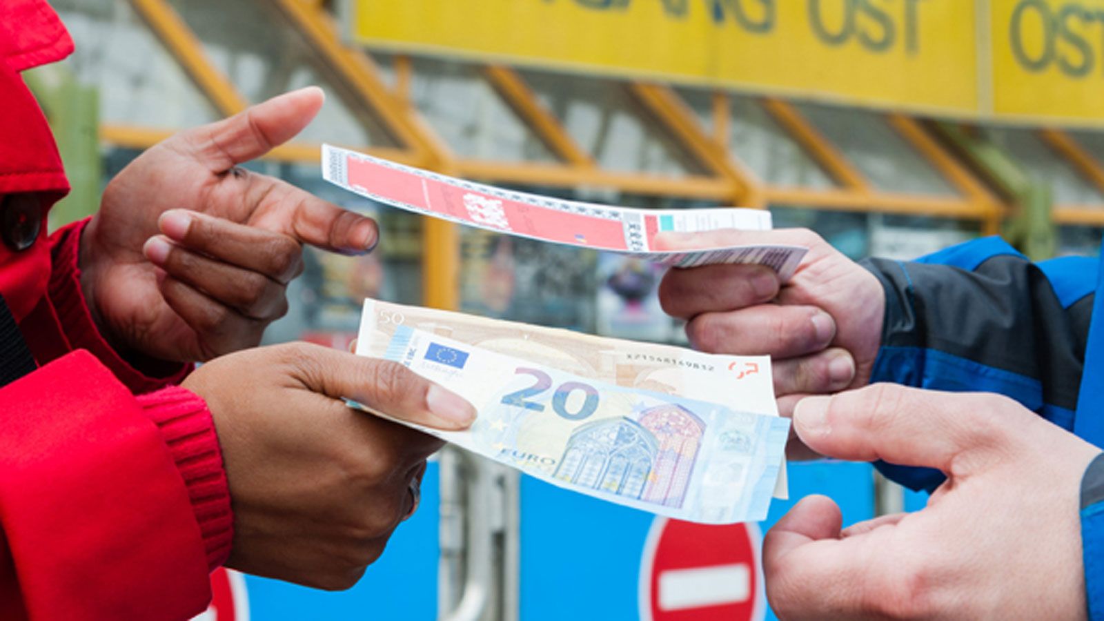 Two people are exchanging money to purchase a ticket.