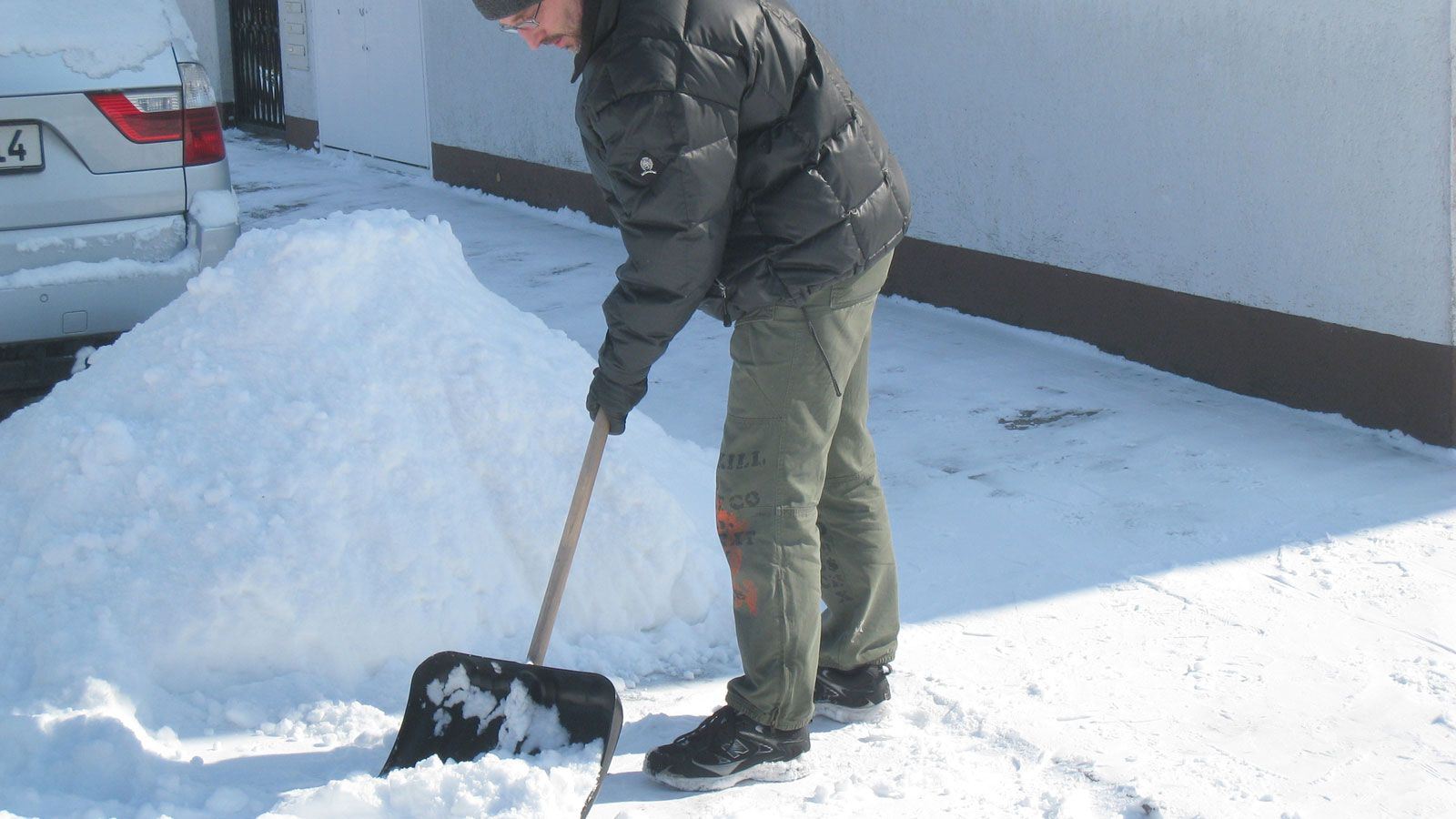 A man shovels snow out of a parking lot to clear the area and improve accessibility.