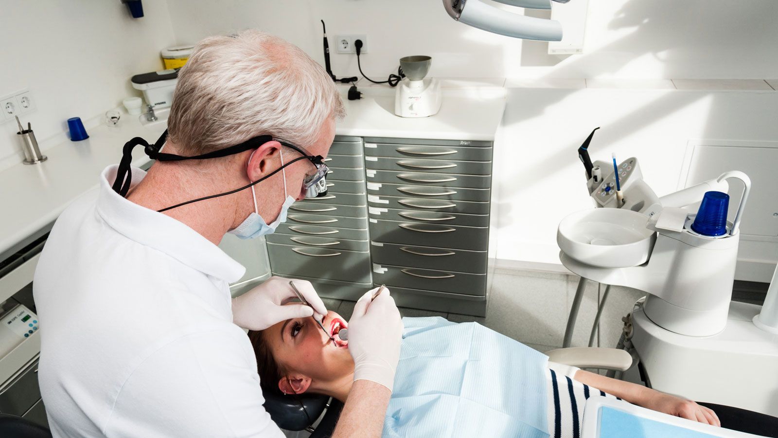 A woman's teeth are examined by a dentist.