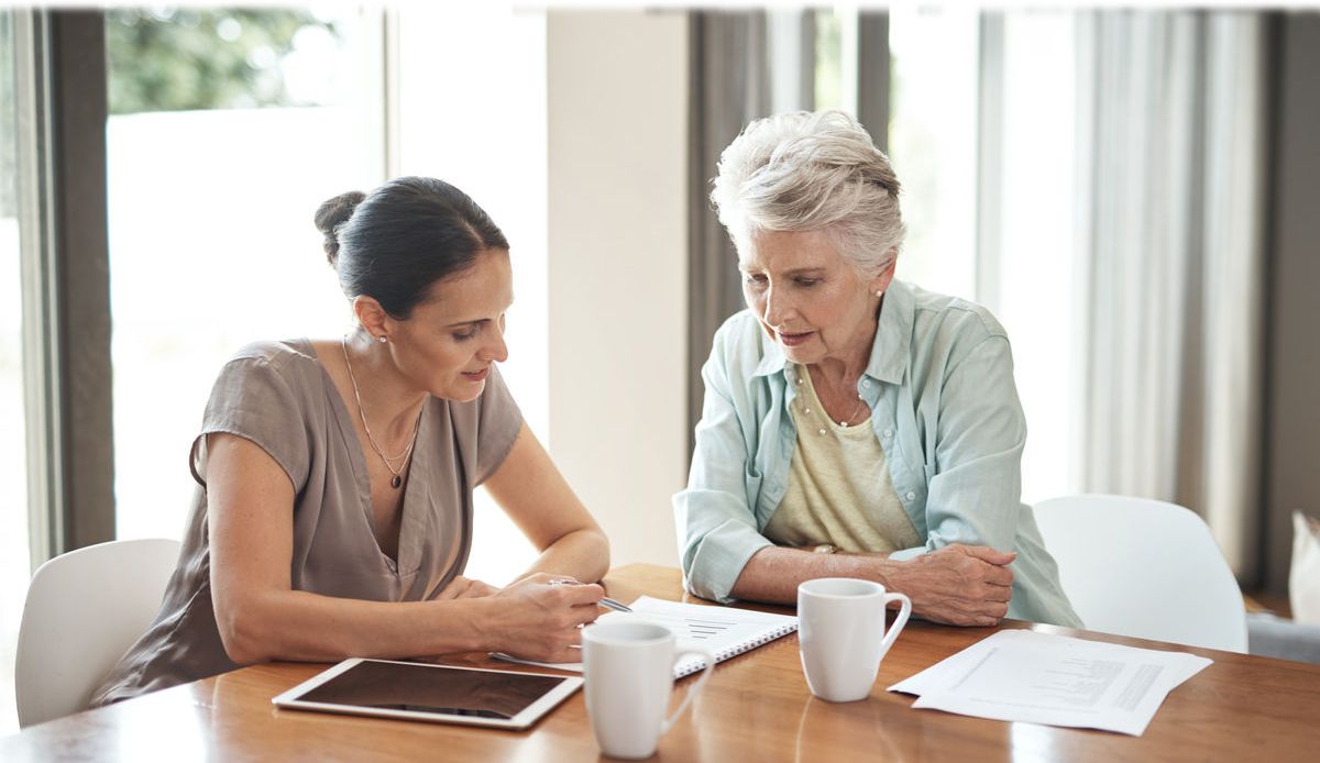 Zwei Frauen lesen zusammen einen Zettel am Tisch