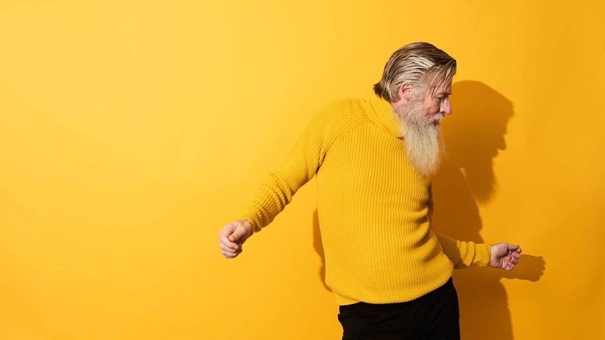 Mann mit gelbem Pullover tanzt vor gelbem Hintergrund